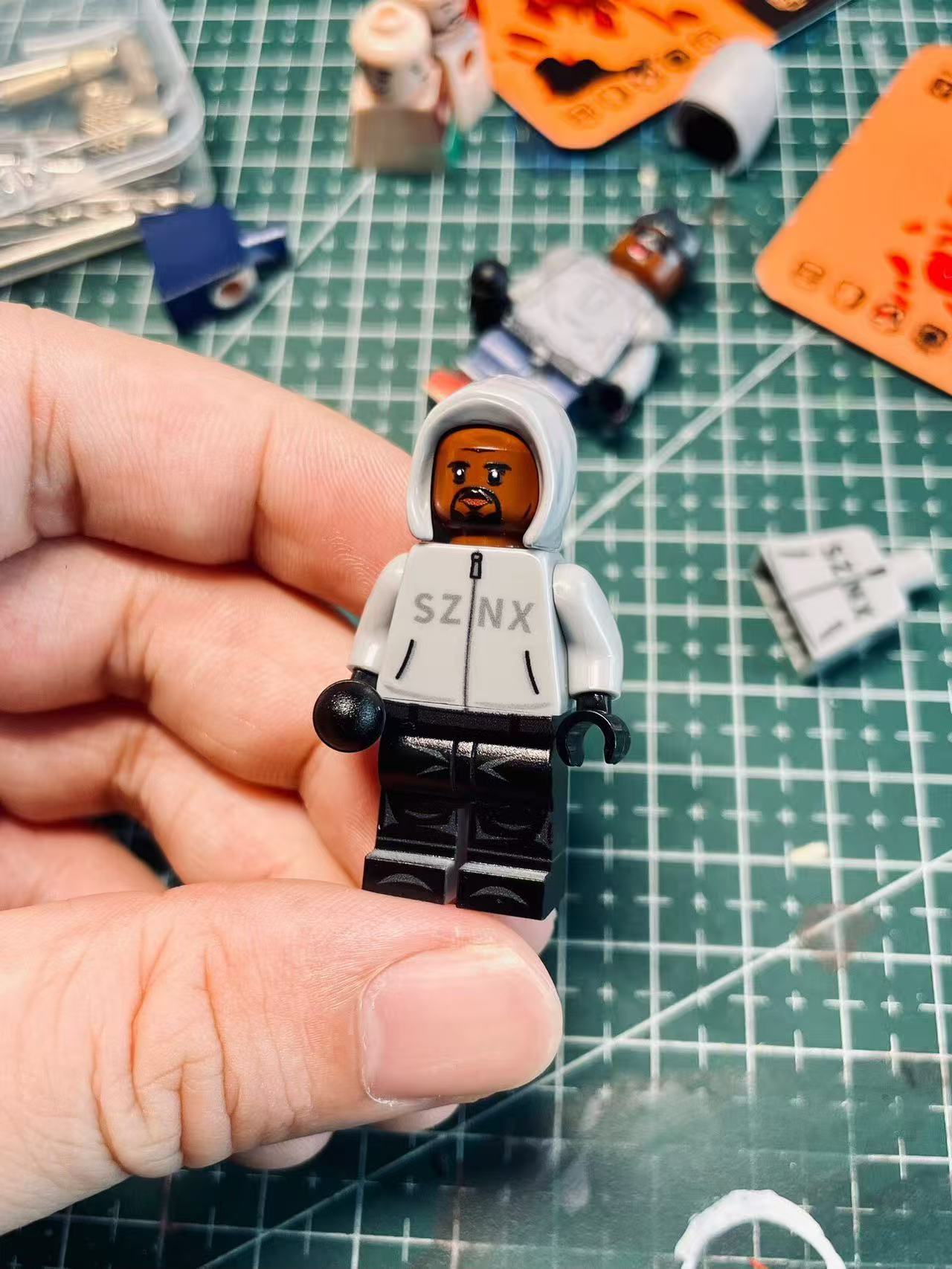Kanye West "Vultures Shanghai 2025" Minifigure, featuring gray hoodie with "SZNX" graphic, dark trousers.